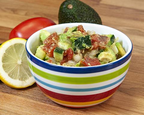Illustrative photo: A bowl of diced cucumber, tomato and avocado salad with a lemon and whole tomato beside it