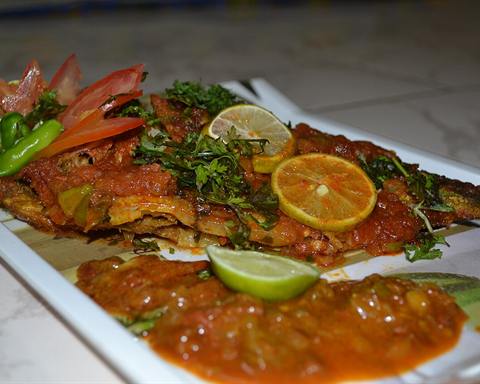 Illustrative photo: A whole baked fish in tomato sauce with herbs and lime slices