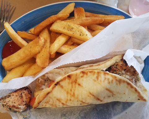 Illustrative photo: A chicken souvlaki pita with tzatziki and tomato, served with french fries