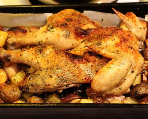 Illustrative photo: A roasted chicken on a bed of potatoes in a baking pan