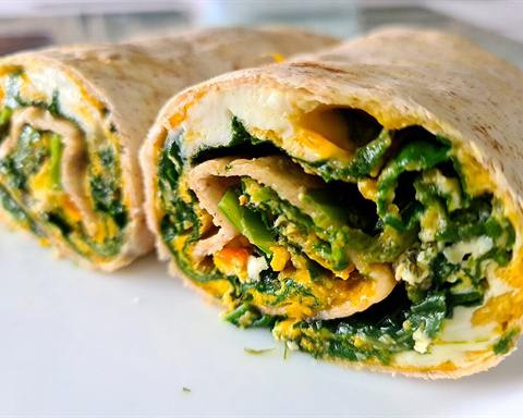 Illustrative photo: A tortilla wrap filled with spinach and egg, cut in half