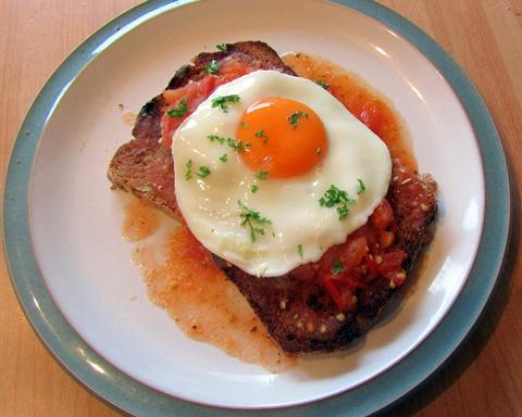 Illustrative photo: A fried egg on toast with tomato relish and fresh herbs on a plate