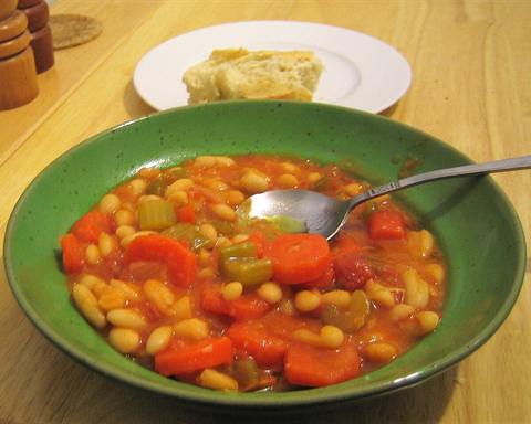 Illustrative photo: White bean soup with carrots, celery and tomato in a green bowl