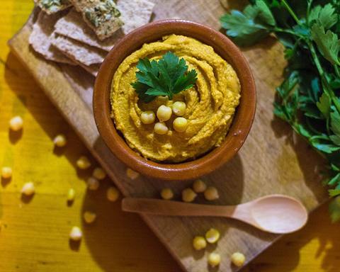 Illustrative photo: A bowl of hummus topped with whole chickpeas and parsley on a wooden board