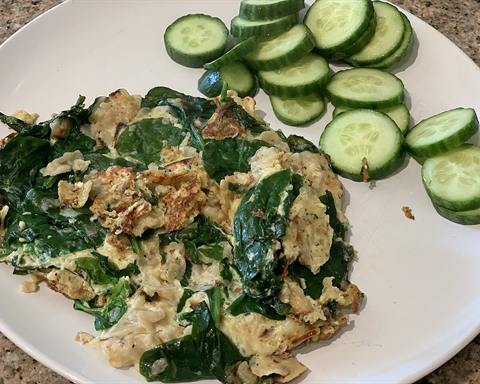 Illustrative photo: Scrambled eggs with spinach and sliced cucumber on a plate