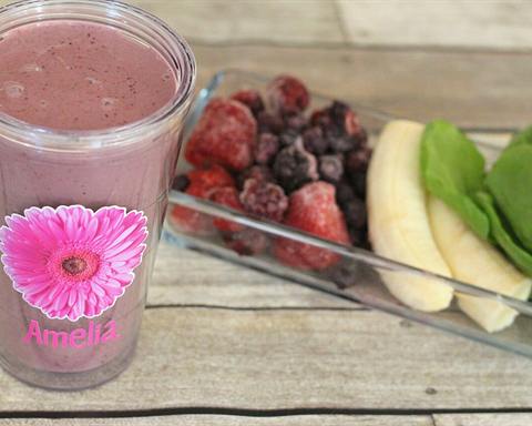 Illustrative photo: A fruit and Greek yogurt smoothie in a glass, with frozen berries, banana and spinach beside it