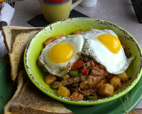 Illustrative photo: A breakfast hash of diced potato and peppers topped with two fried eggs, with toast