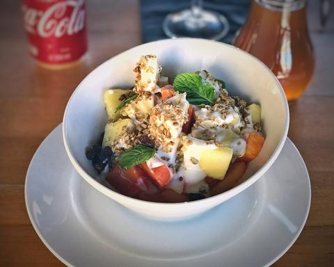 Illustrative photo: A white bowl of yogurt with pieces of fruit, granola and mint